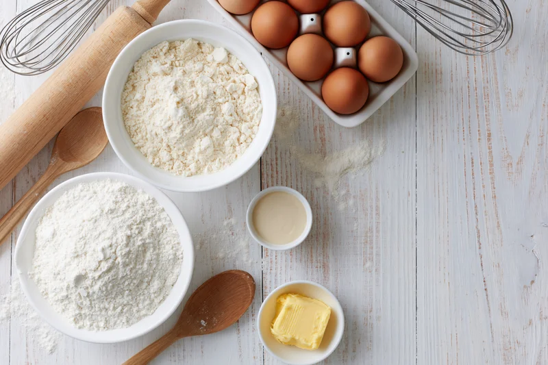 Baking ingredients arranged on a white wooden surface with copyspace