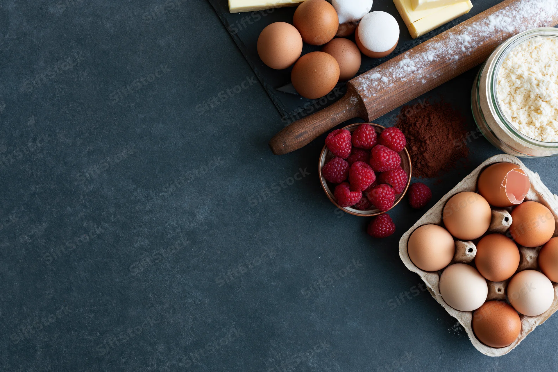 Baking ingredients arranged on dark countertop with copyspace