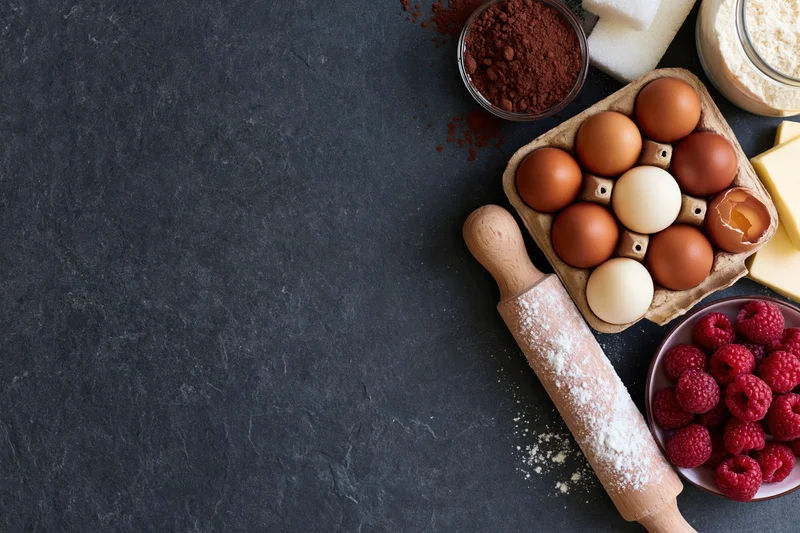 Baking ingredients arranged on dark slate countertop with copyspace