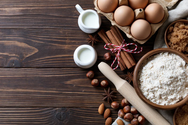 Baking ingredients arranged on a dark wooden table with copyspace on the left