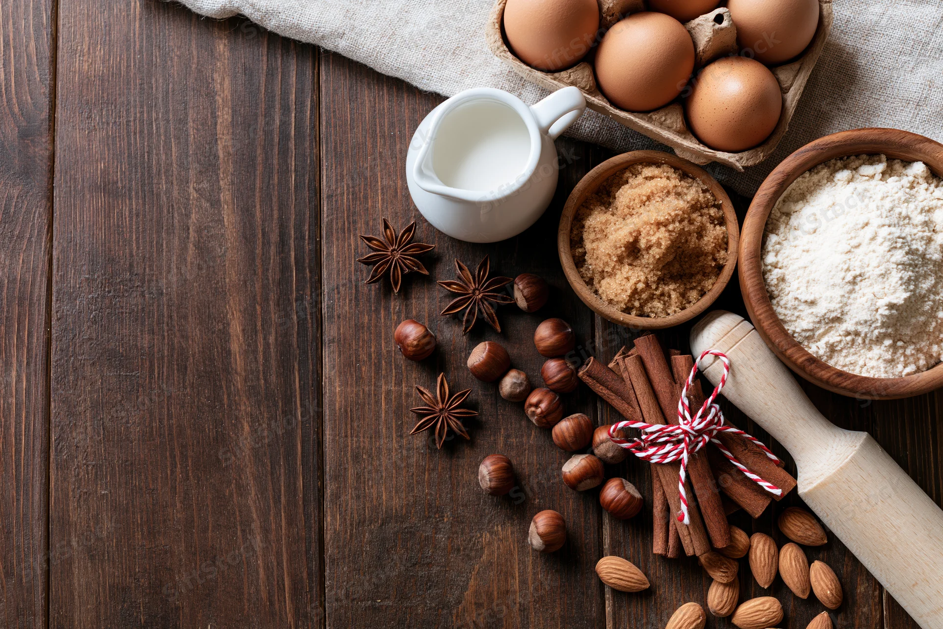 Baking ingredients arranged on dark wooden surface with copyspace on left