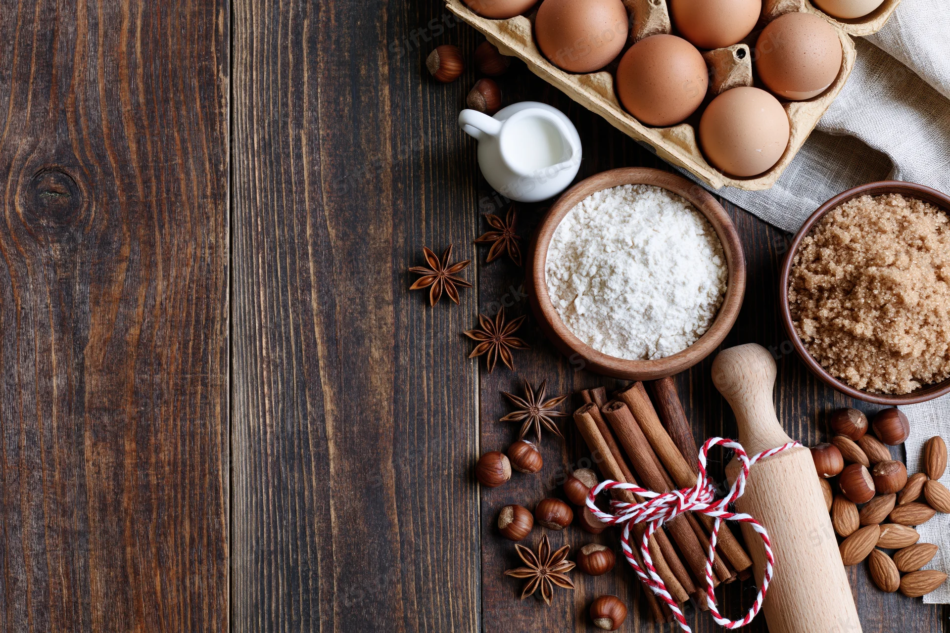 Baking ingredients arranged on dark wooden surface with copyspace on left