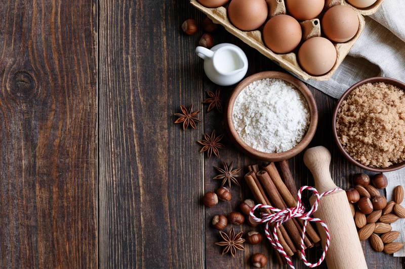 Baking ingredients arranged on dark wooden surface with copyspace on left