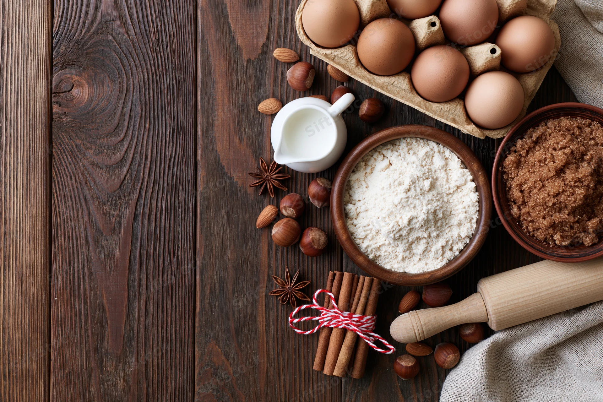 Baking ingredients arranged on a dark wooden countertop with copyspace on the left