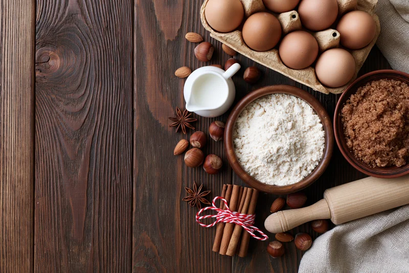 Baking ingredients arranged on a dark wooden countertop with copyspace on the left