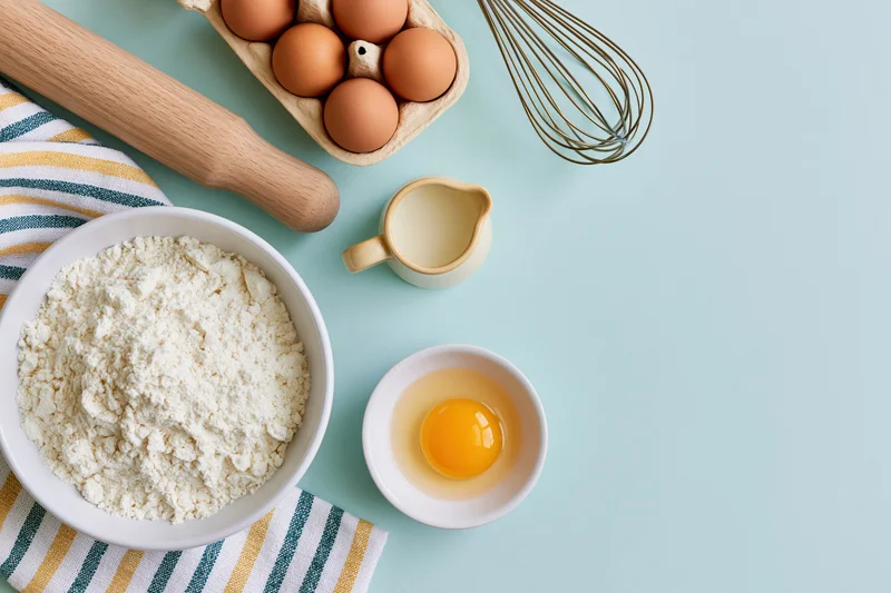 Baking ingredients arranged on a blue surface with copyspace