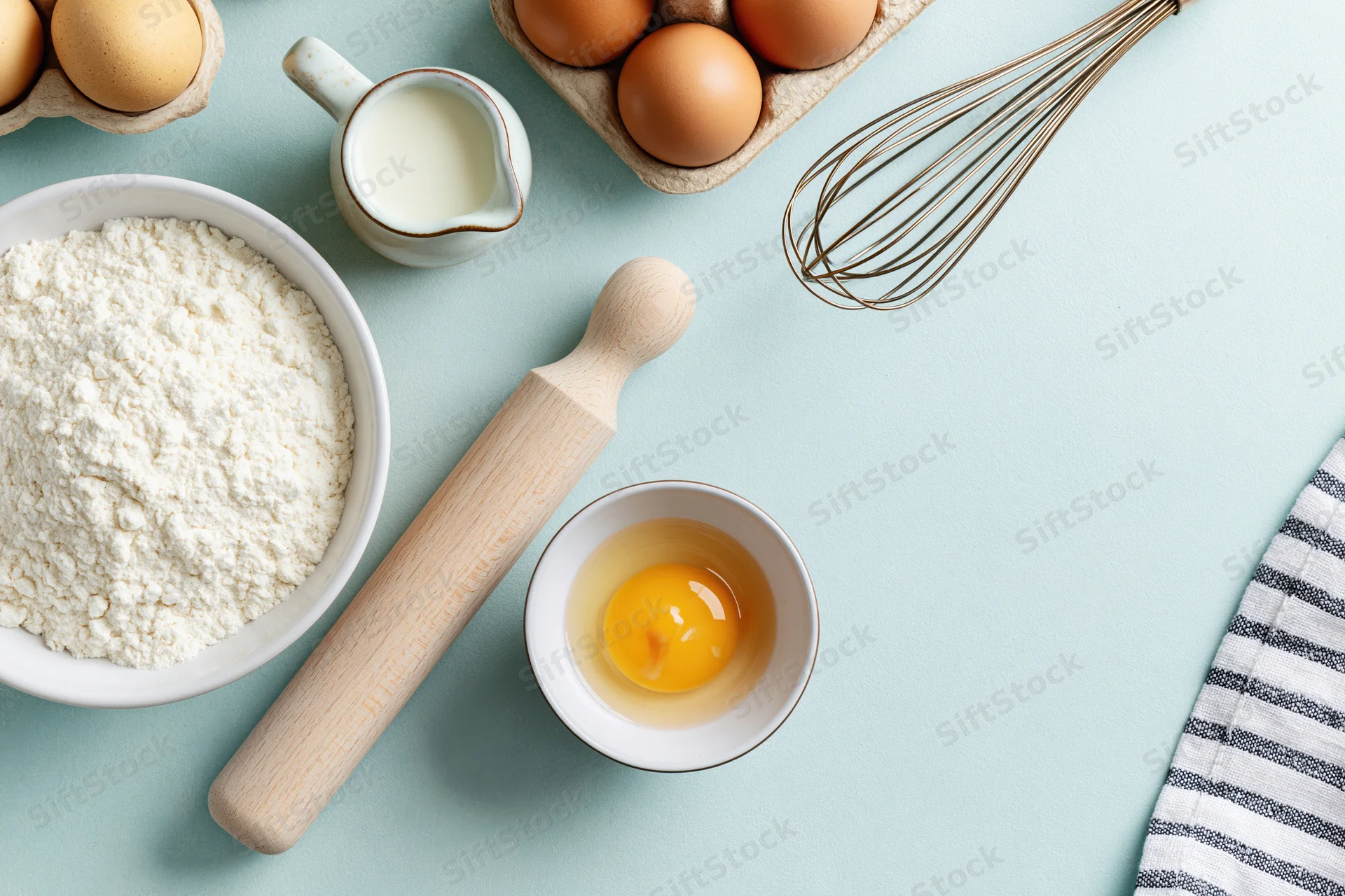 Baking ingredients arranged on a blue countertop with copyspace