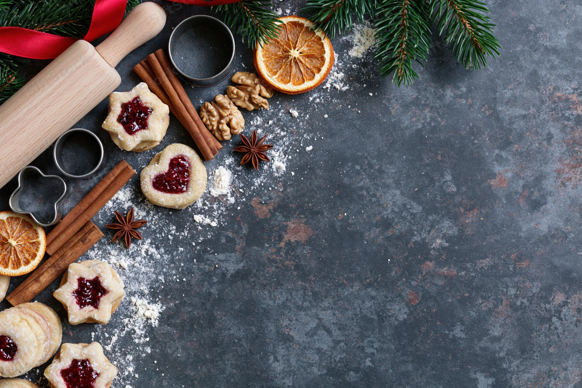 Christmas cookies with jam and spices arranged on dark countertop with copyspace