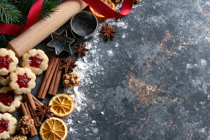 Christmas cookies with jam and spices arranged on dark countertop with copyspace