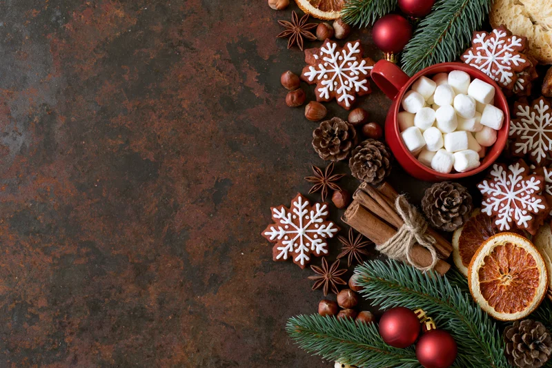 Christmas decorations and treats arranged on a dark textured surface with copyspace