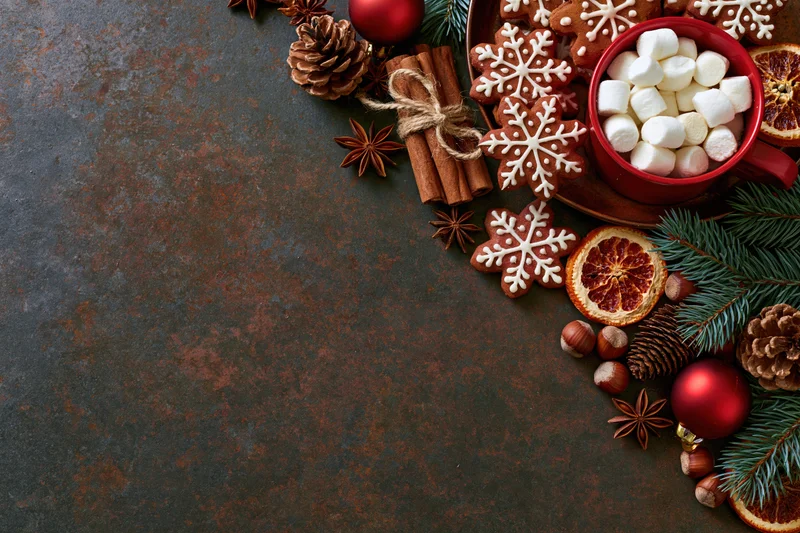 Christmas decorations and treats arranged on dark textured surface with copyspace