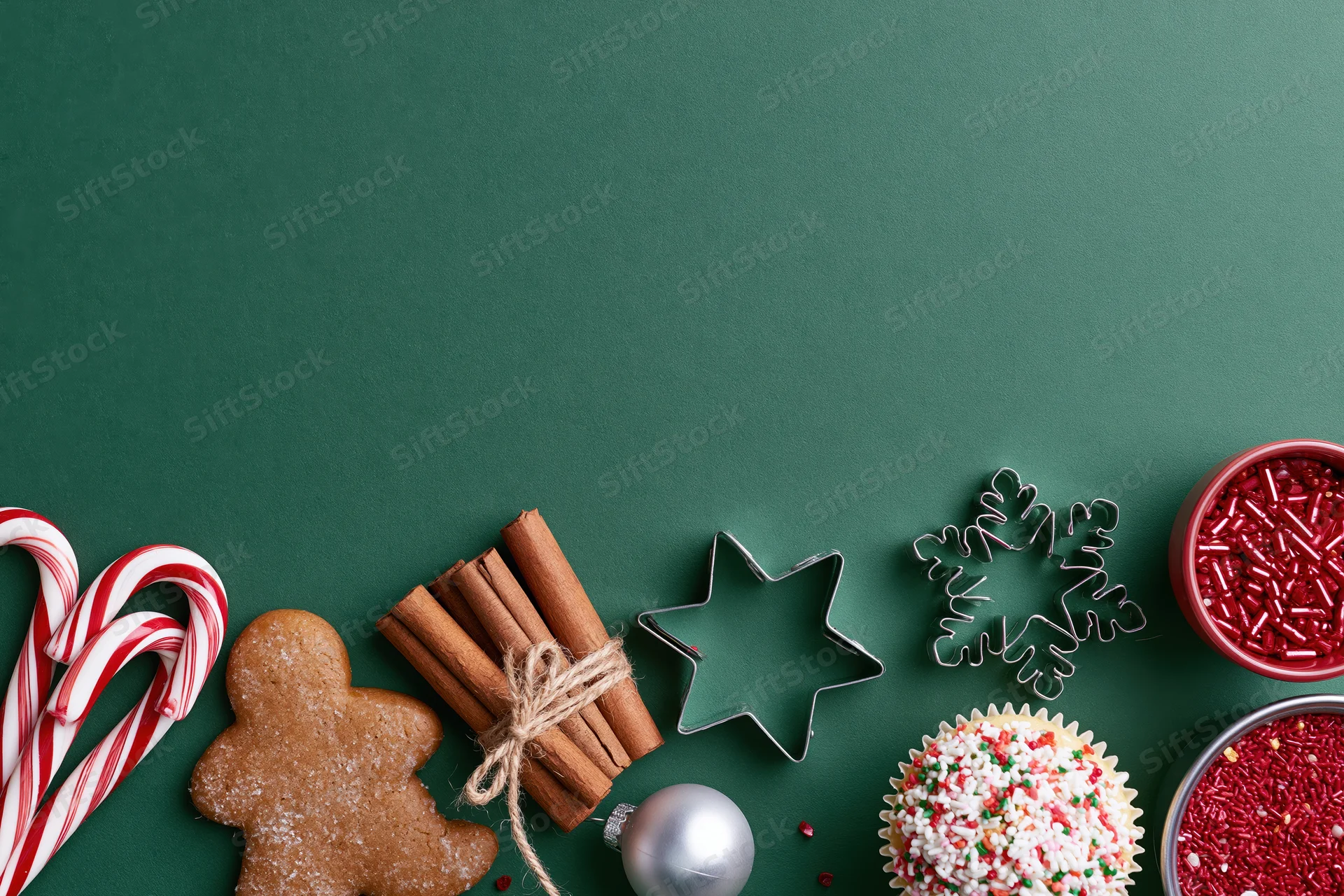 Christmas treats and baking tools arranged on green surface with copyspace
