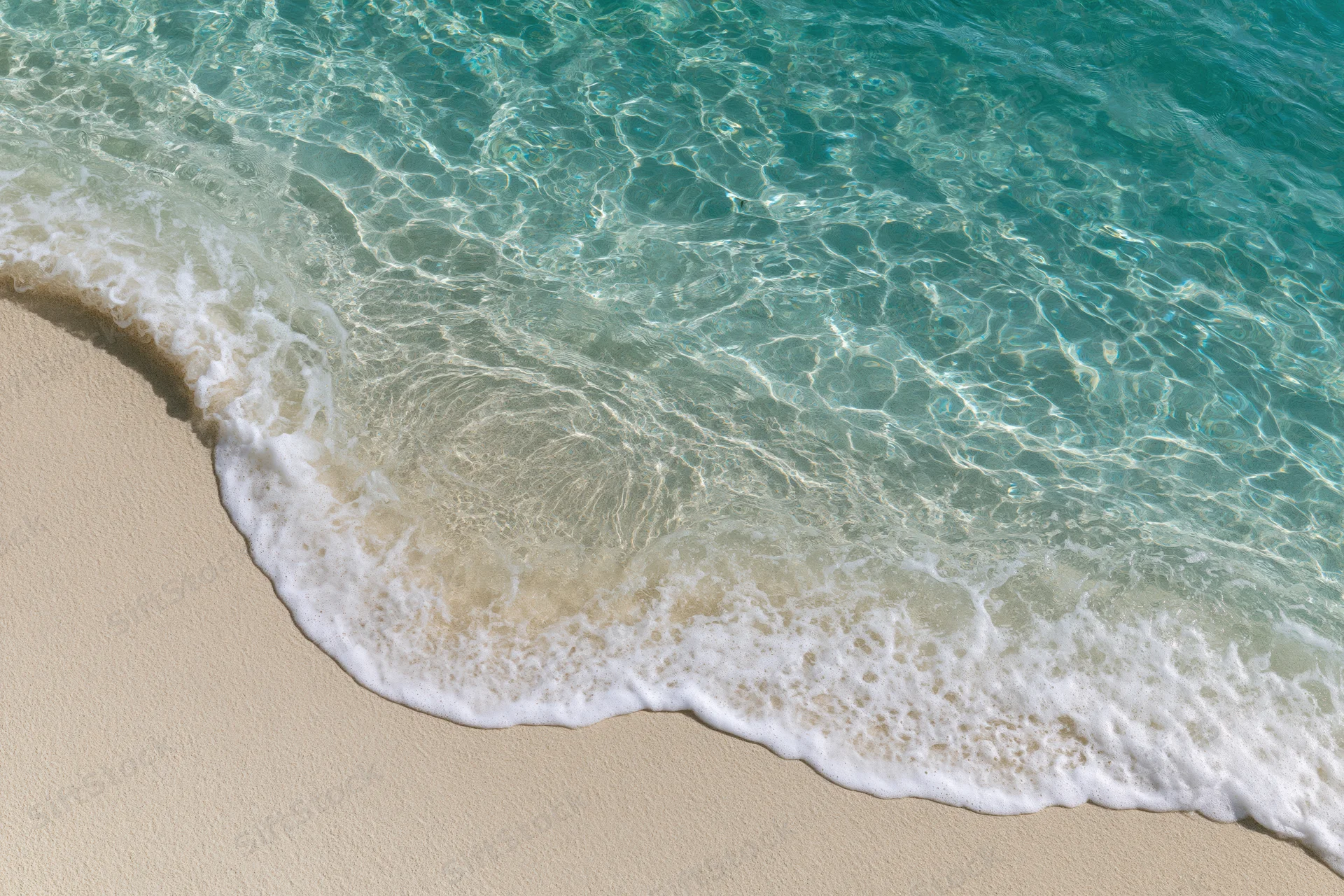 Turquoise ocean wave breaking onto sandy beach with white foam