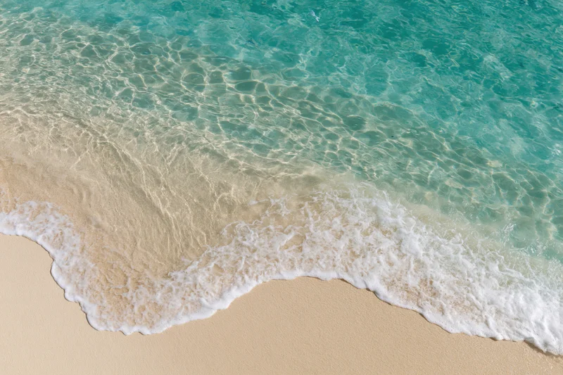 Gentle waves breaking on a sandy beach with clear turquoise water
