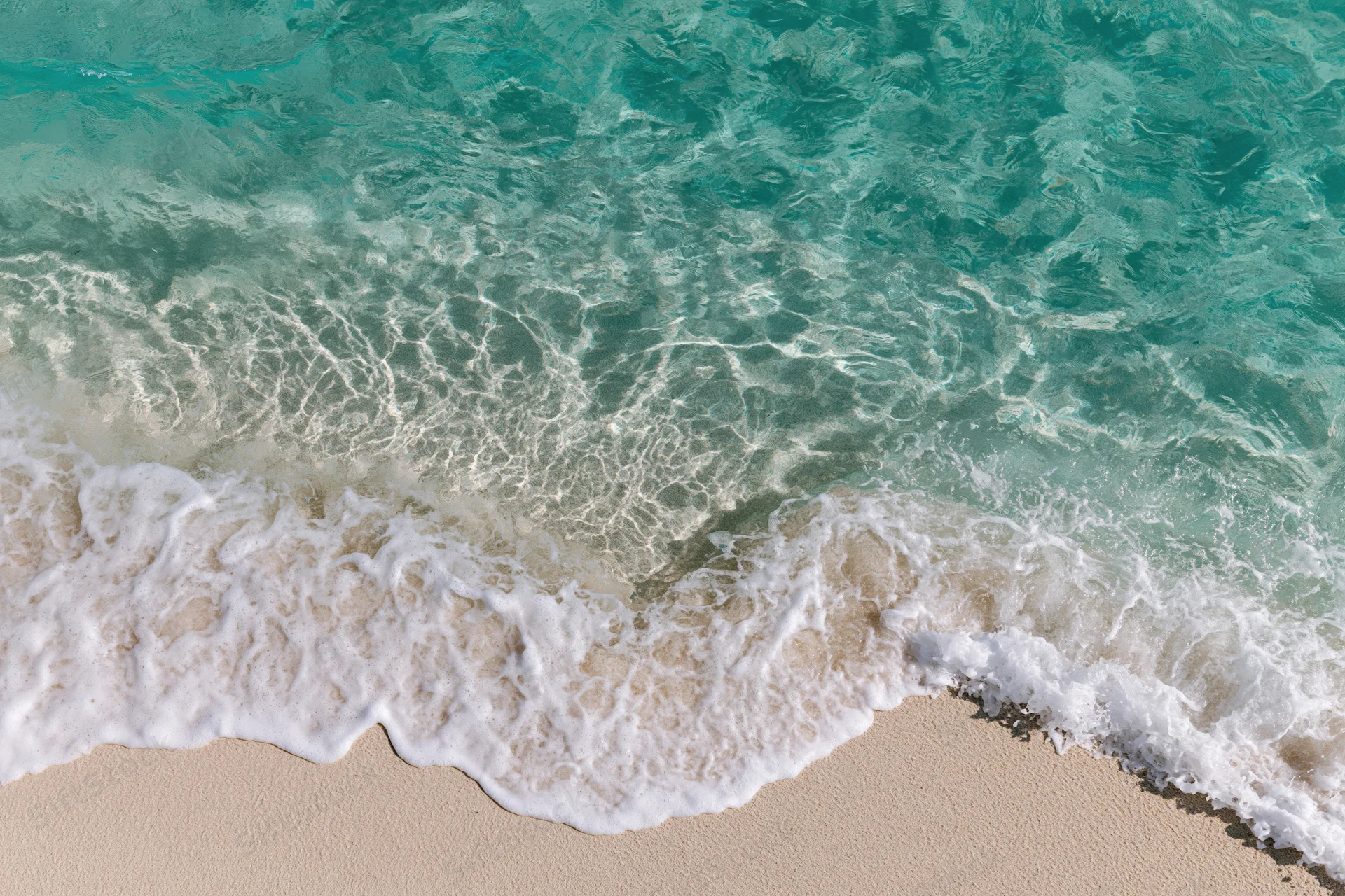 Waves breaking on sandy beach with white foam and turquoise water