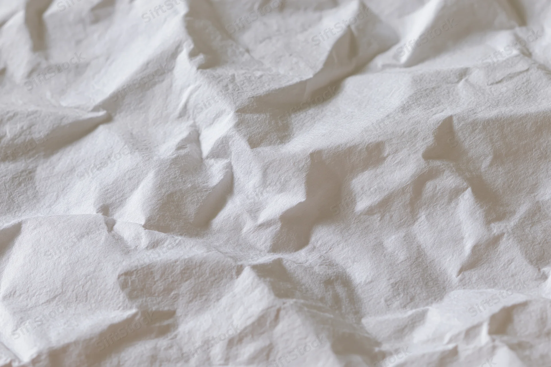 Crumpled white paper texture with folds and creases filling the frame