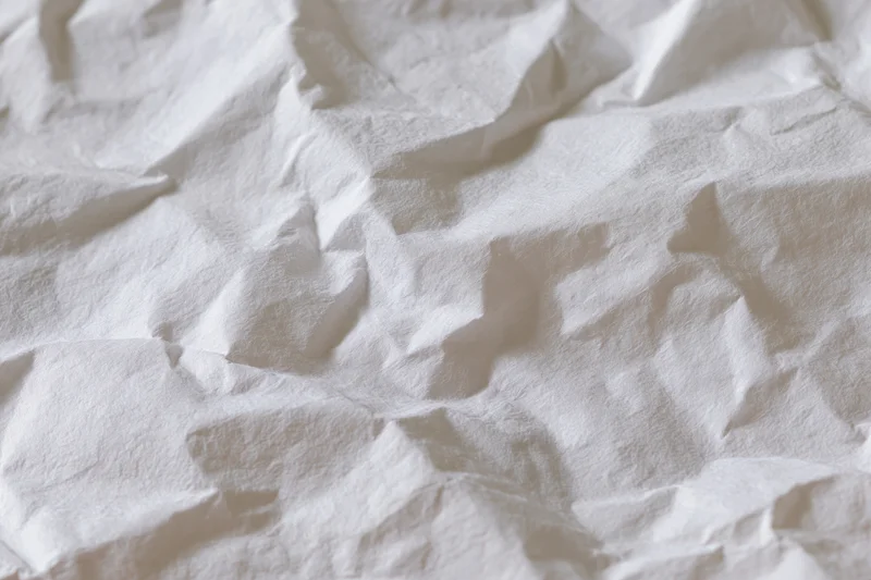 Crumpled white paper texture with folds and creases filling the frame