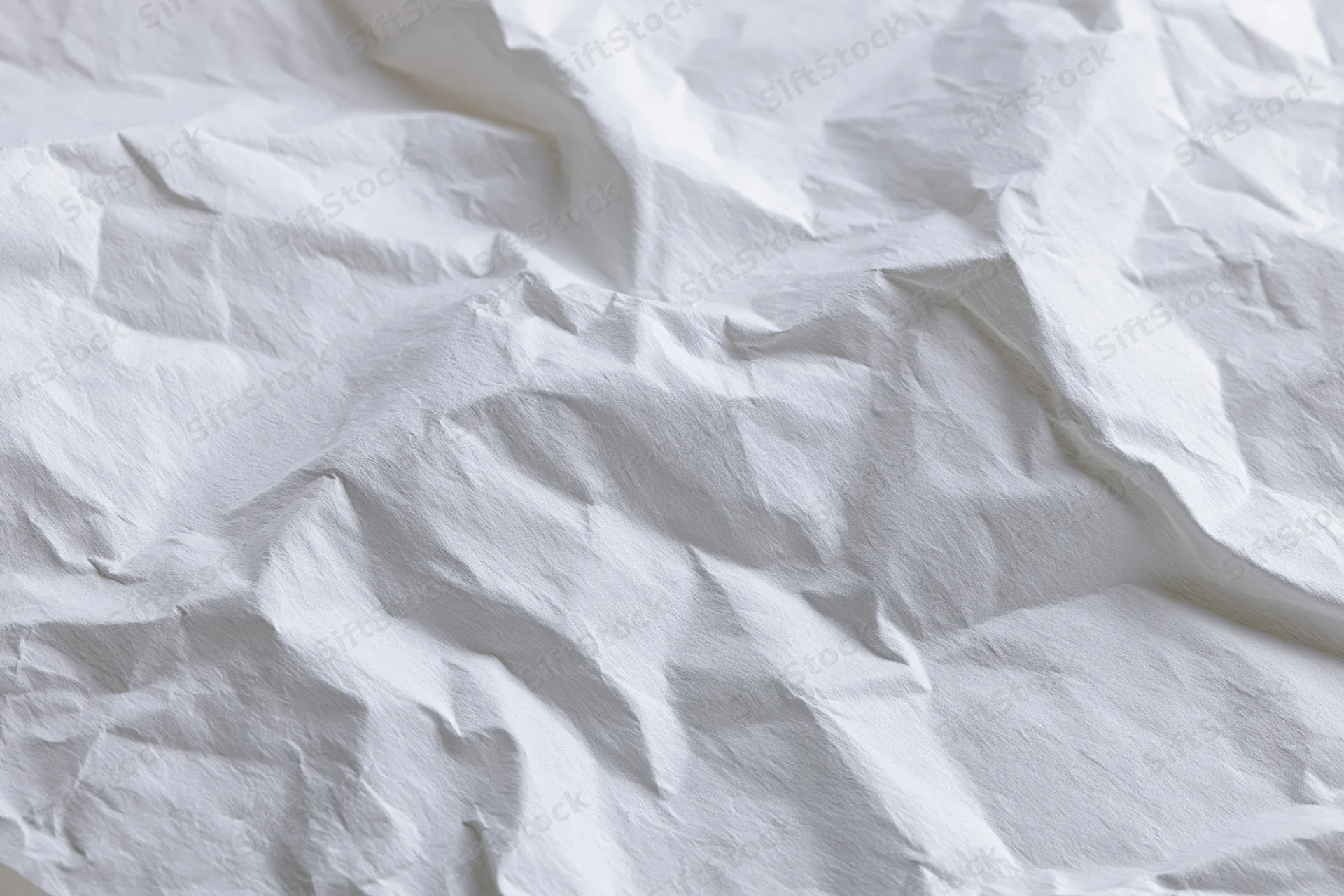 Crumpled white paper with folds and creases filling the frame