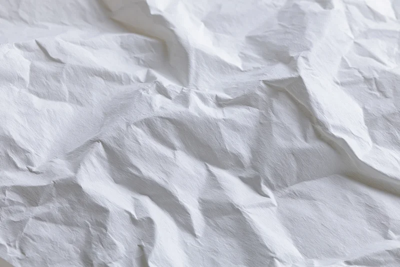 Crumpled white paper with folds and creases filling the frame