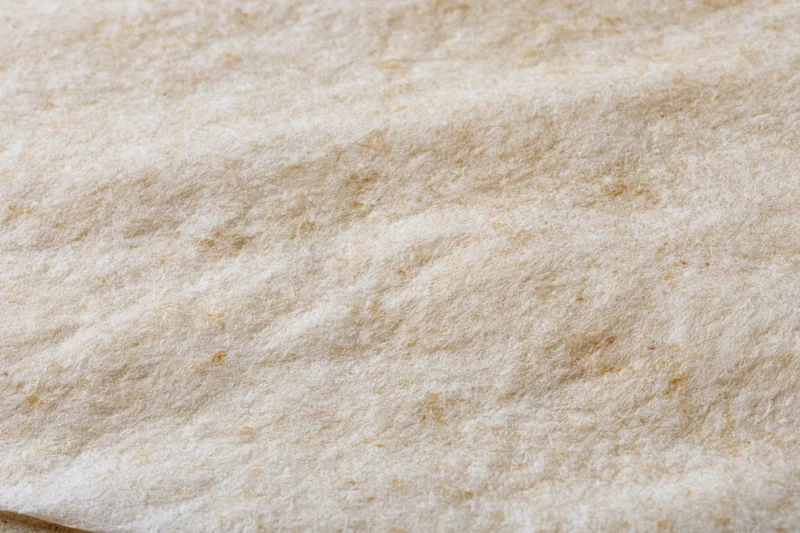 Closeup of textured beige paper surface with natural fiber grain and soft matte finish