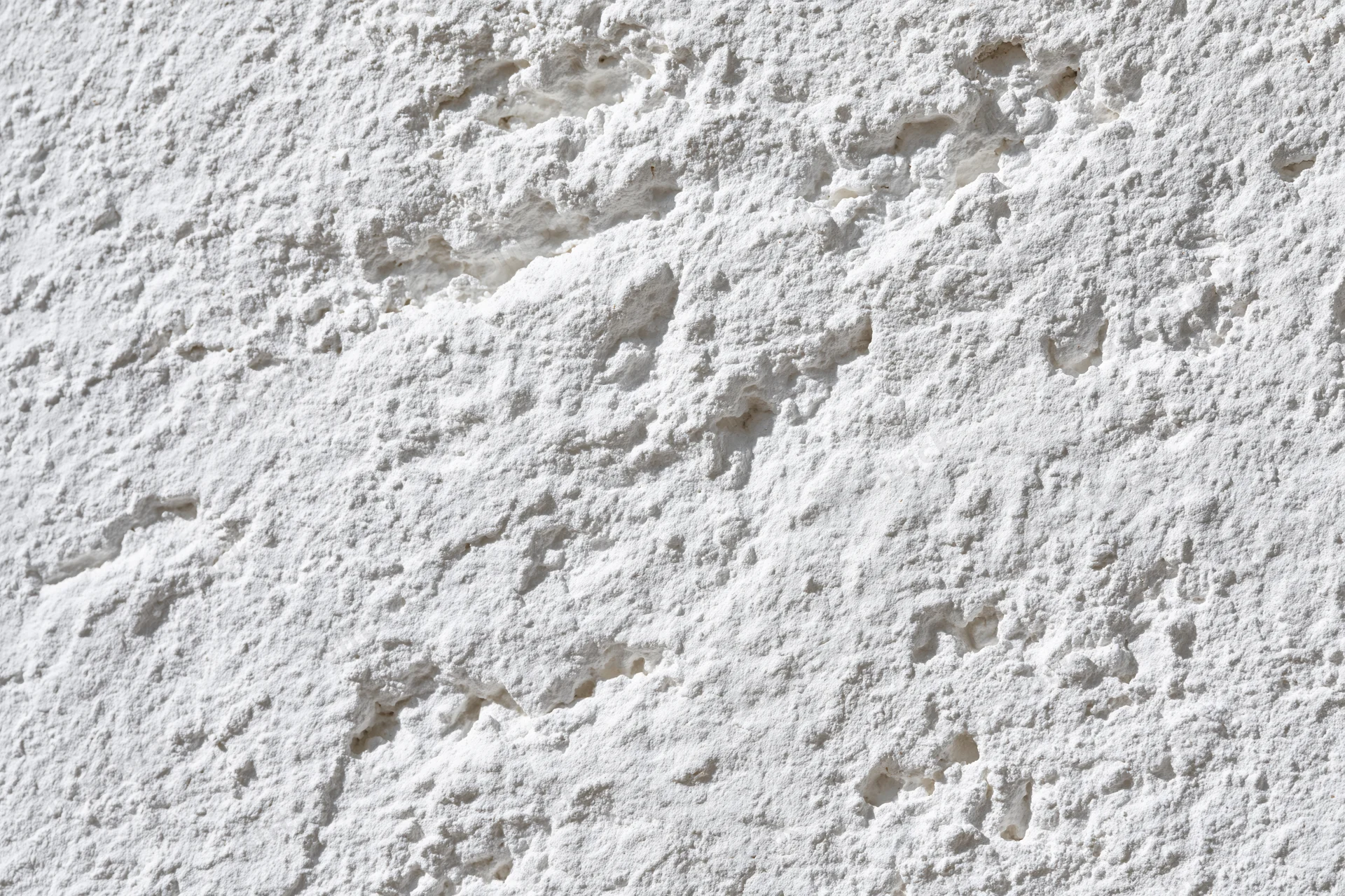 Close-up of rough white plaster texture on a wall surface