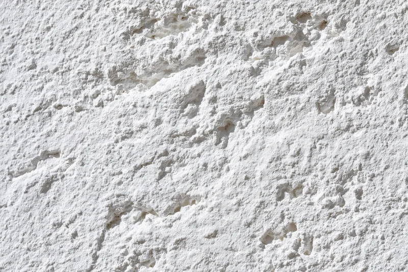 Close-up of rough white plaster texture on a wall surface