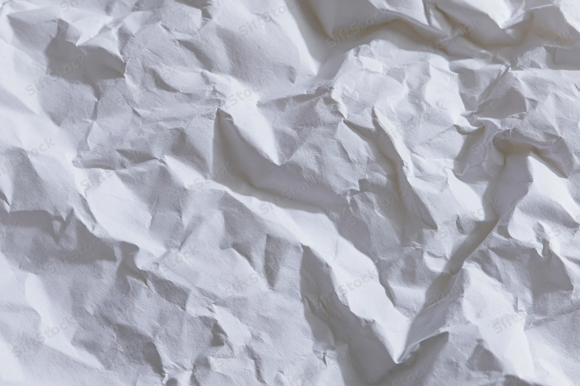Crumpled white paper texture filling the frame with folds and shadows