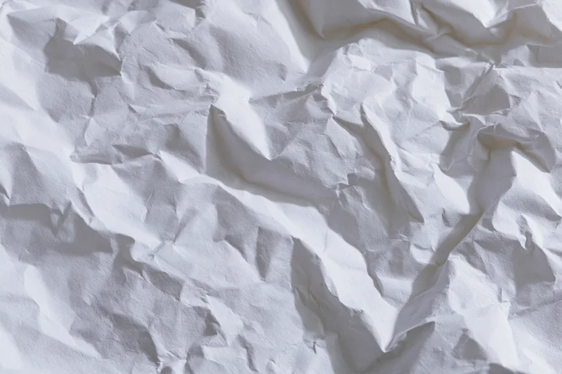 Crumpled white paper texture filling the frame with folds and shadows