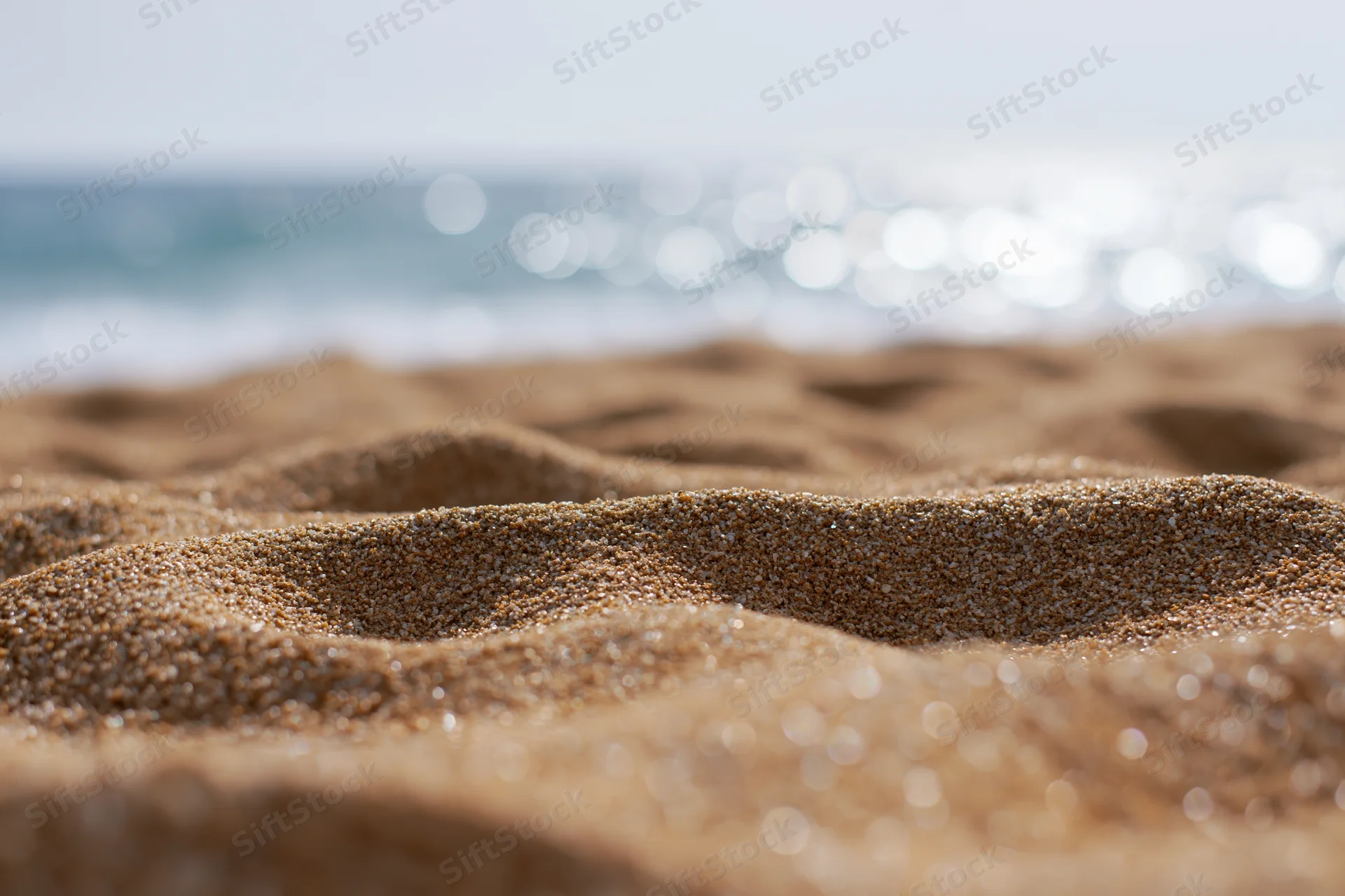 Closeup of textured sand on a beach with ocean waves in the background