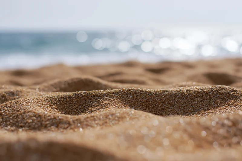 Closeup of textured sand on a beach with ocean waves in the background