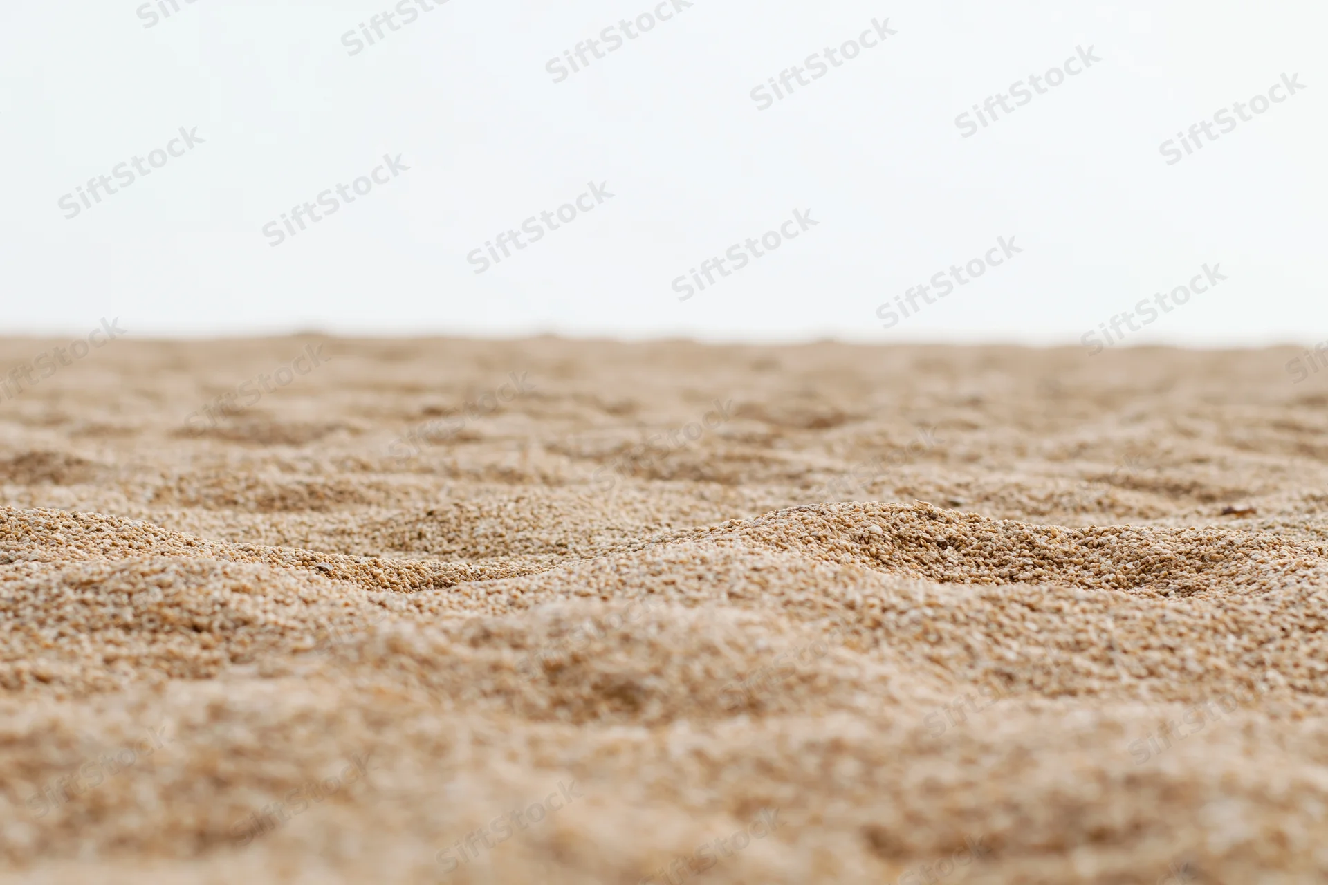 Closeup of textured sand surface with shallow depth of field and soft lighting
