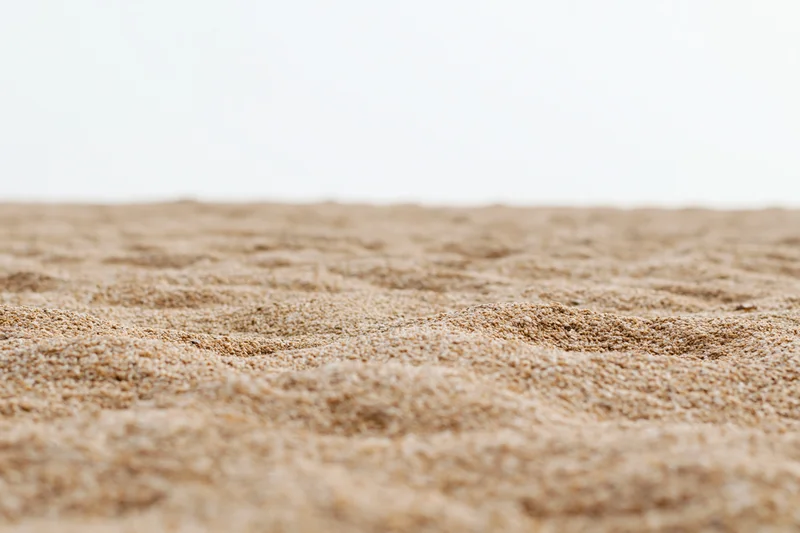 Closeup of textured sand surface with shallow depth of field and soft lighting