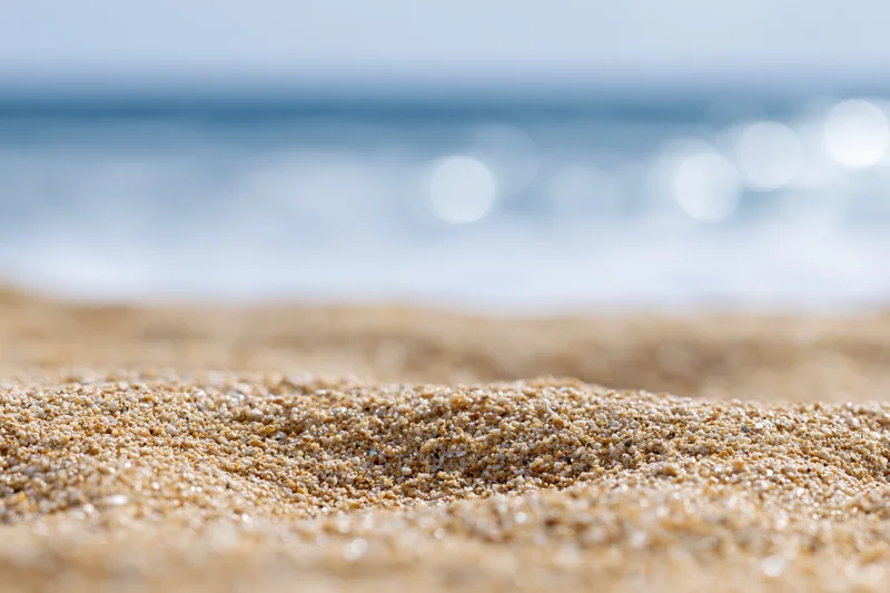 Closeup of textured sand on a beach with ocean in the background