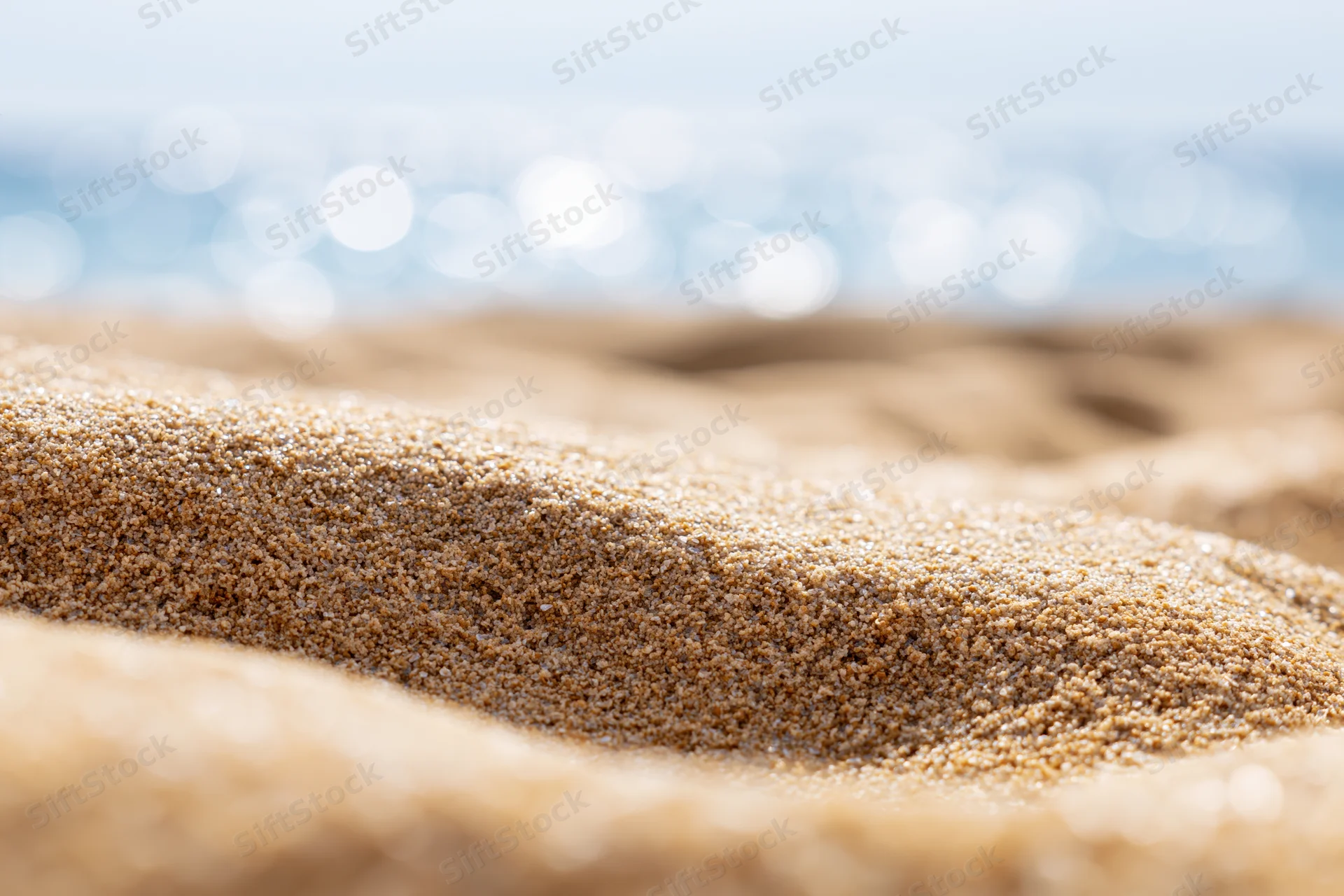Closeup of textured sand on a beach with ocean in the background