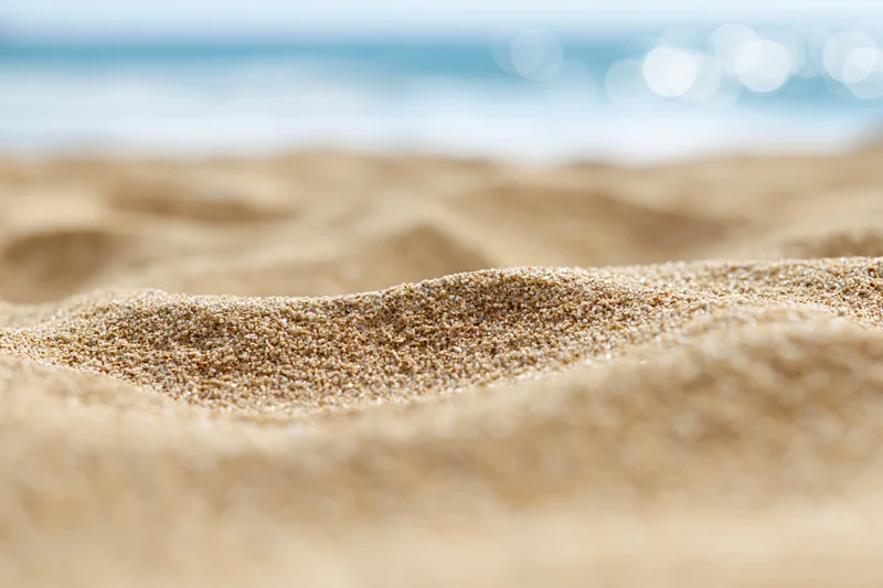 Closeup of textured sand on a beach with ocean in the background
