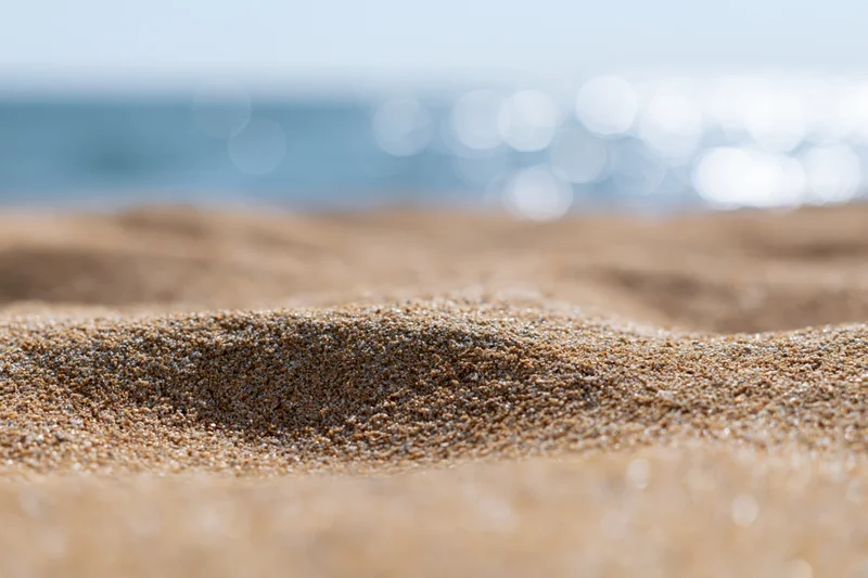 Closeup of textured sand on a beach with ocean in the background