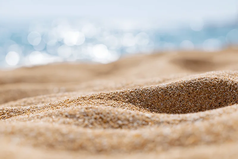 Closeup of textured sand on a beach with blurred ocean in the background