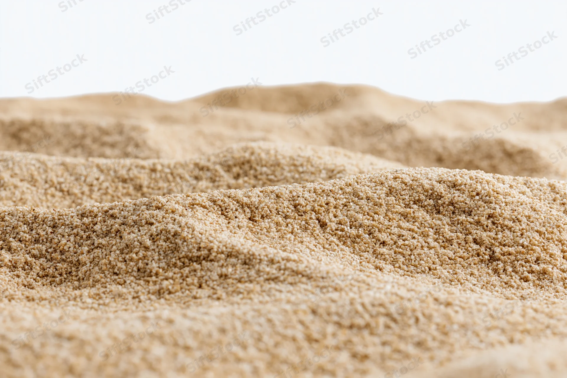 Closeup of textured sand surface with fine granules forming undulating patterns against white background
