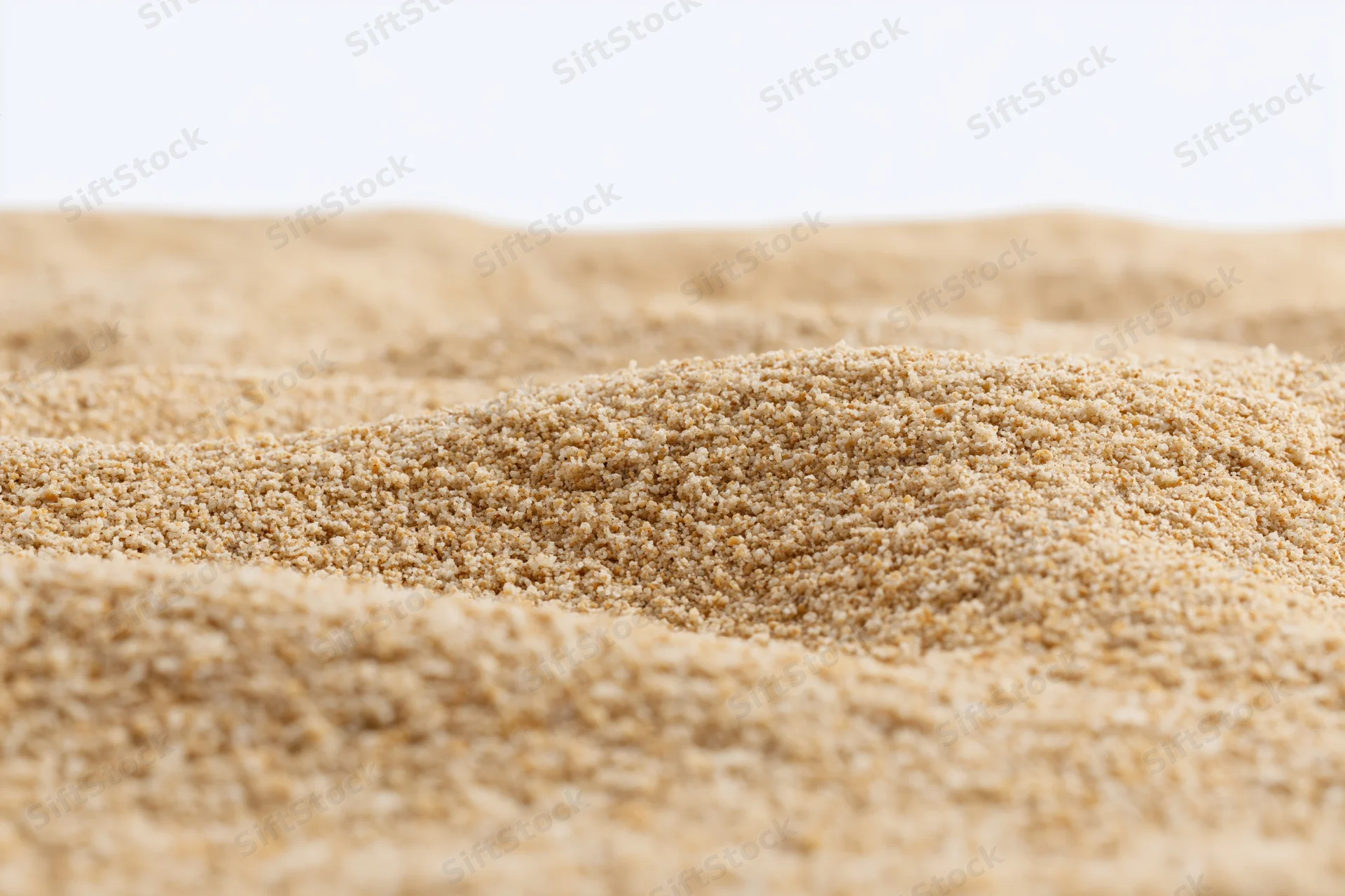 Closeup of undulating sand dunes on a plain white background