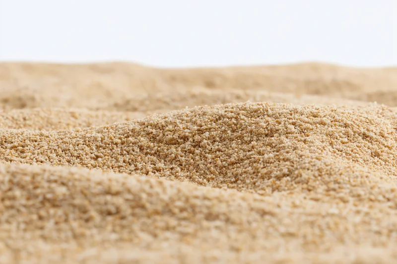 Closeup of undulating sand dunes on a plain white background
