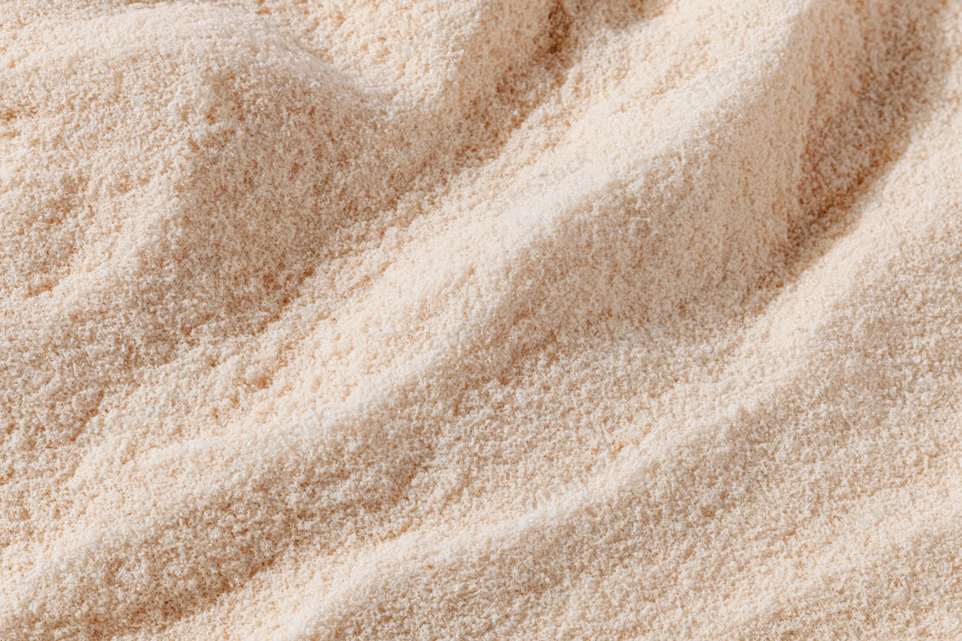 Closeup of fine white flour piled in soft waves showing texture and grain