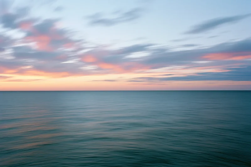 Calm ocean surface under pastel sunset sky at twilight