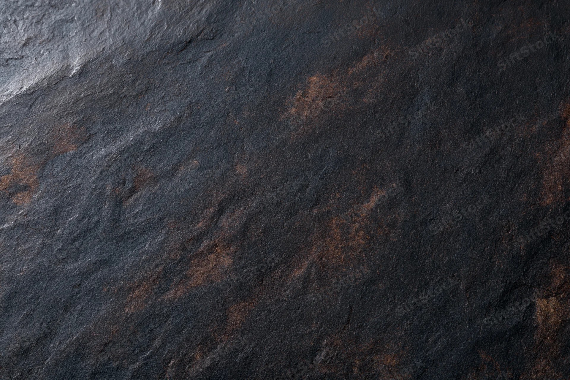 Dark weathered slate surface with rust stains and rough texture