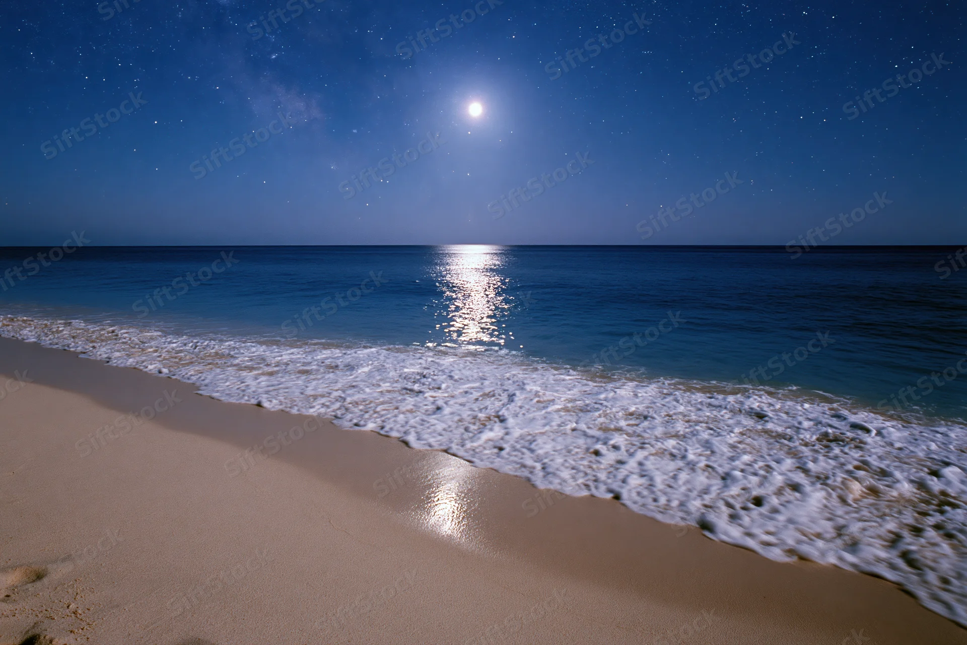 Moonlit beach at night with waves washing onto sand under starry sky