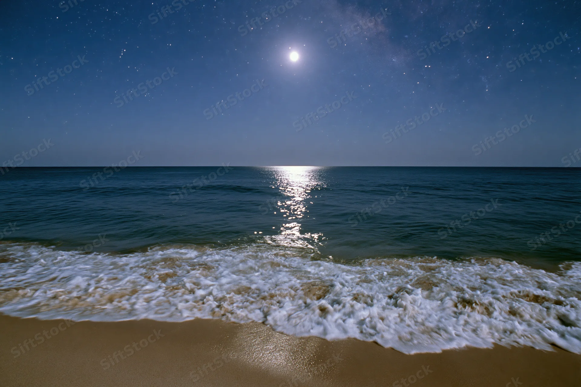 Moonlit ocean waves rolling onto sandy beach under starry night sky