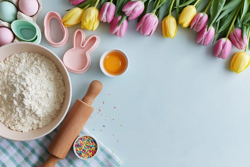Easter baking ingredients and tulips arranged on a table with copyspace
