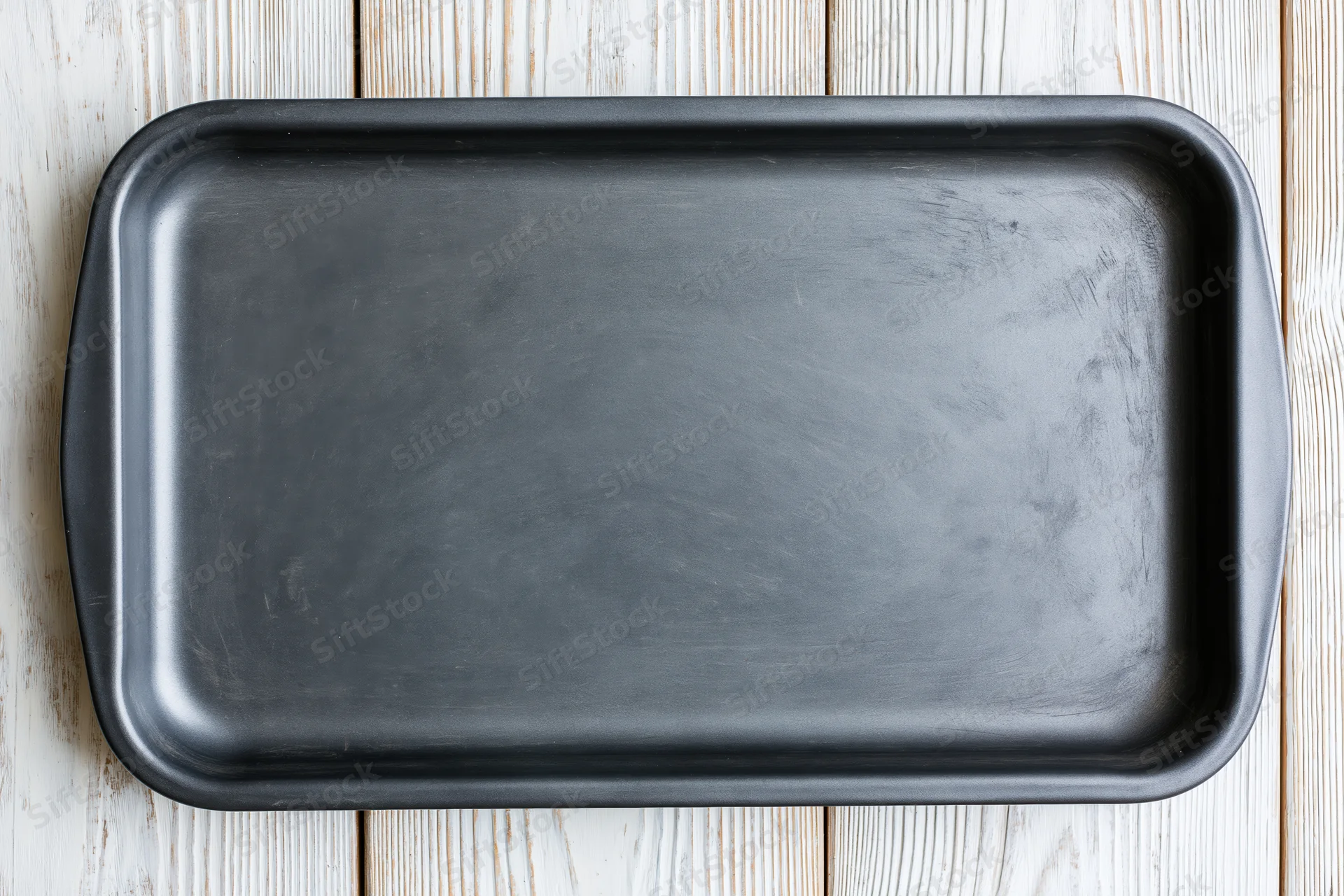 Black nonstick baking pan on wooden surface viewed from above