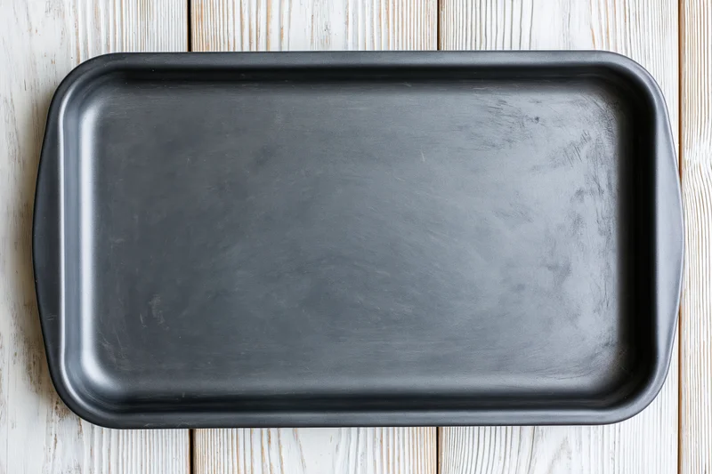 Black nonstick baking pan on wooden surface viewed from above
