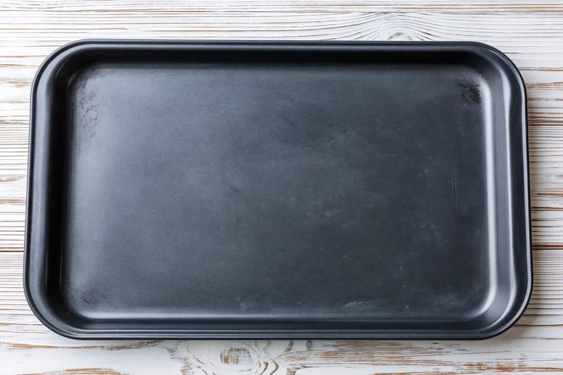 Black nonstick baking tray on white wooden surface