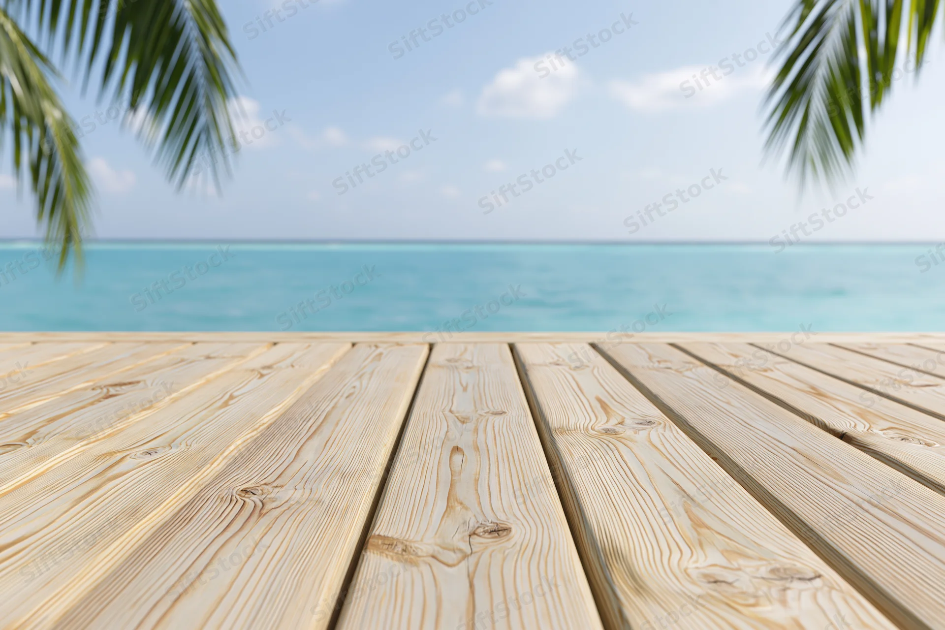 Wooden deck overlooking turquoise ocean with palm fronds framing the view